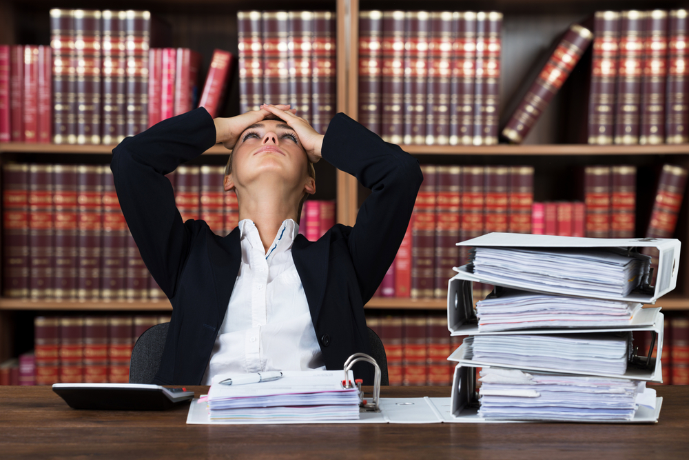 lawyer surrounded by books looking frustrated